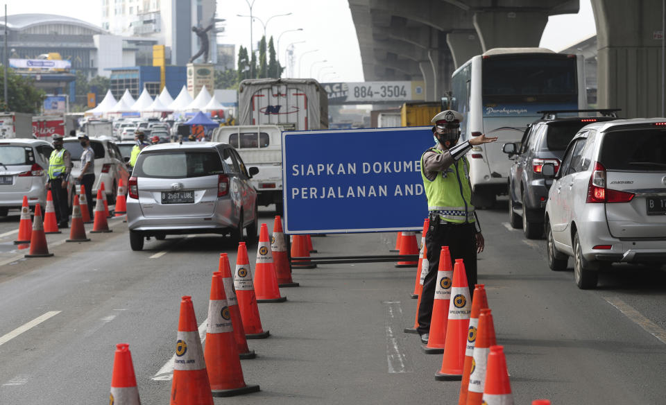 Indonesian police guard at a checkpoint during the imposition of large-scale restriction to curb the spread of the coronavirus on a toll road in Cikarang, West Java, Indonesia, Thursday, May 6, 2021. Indonesia is prohibiting travel during the popular homecoming period to celebrate Eid al-Fitr. The ban started Thursday and will last for 12 days, exempting only civil servants, police and military officers, and those who need to travel for work. (AP Photo/Achmad Ibrahim)