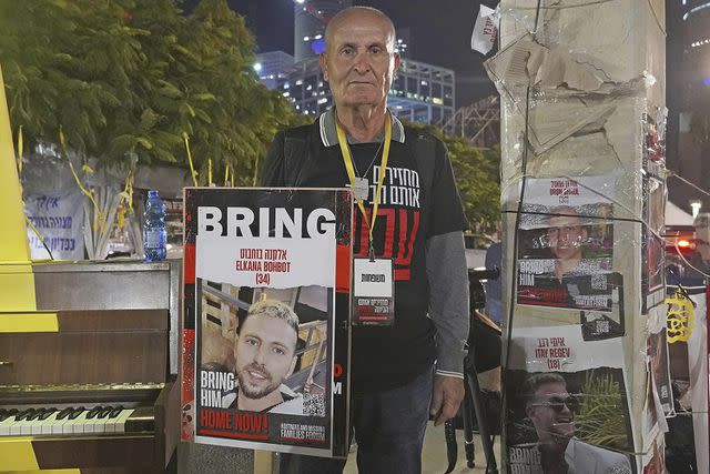 <p>Kyodo via AP Images</p> An Israeli man in a square in Tel Aviv on Nov. 24, 2023, holds a photo of his relative Elkana Bohbot