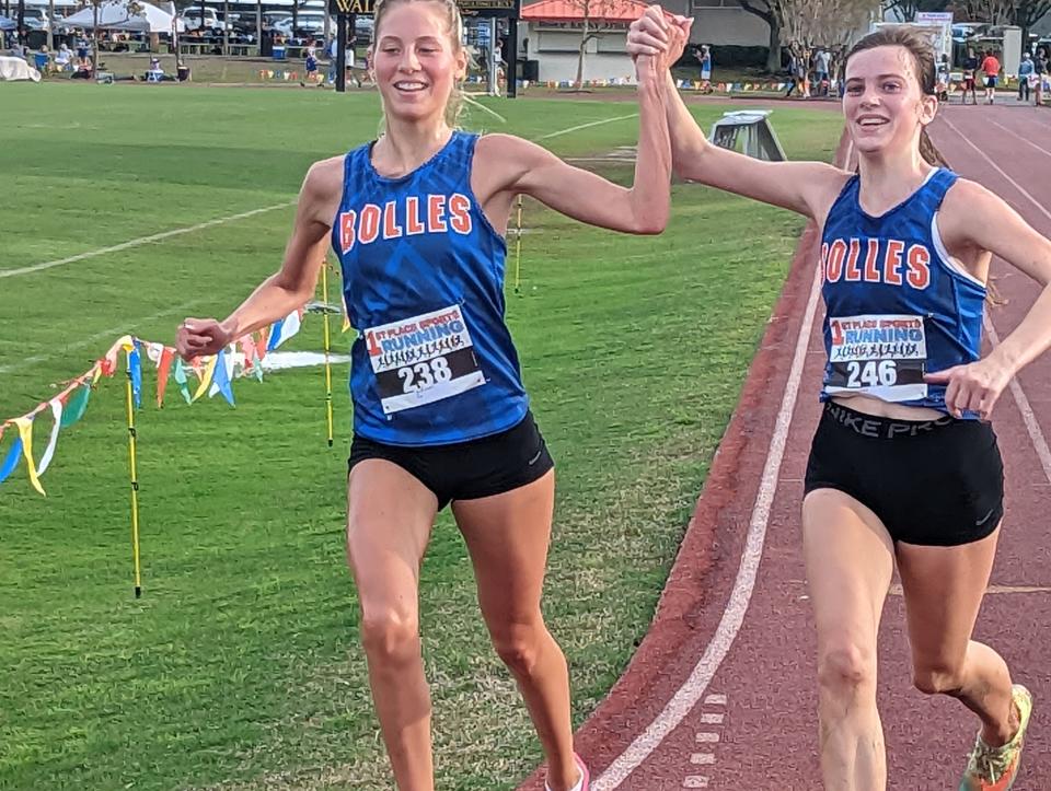 Bolles teammates Jillian Candelino (238) and Ella Mickler (246) raise their arms in celebration upon crossing the finish line in the District 2-2A cross country meet.