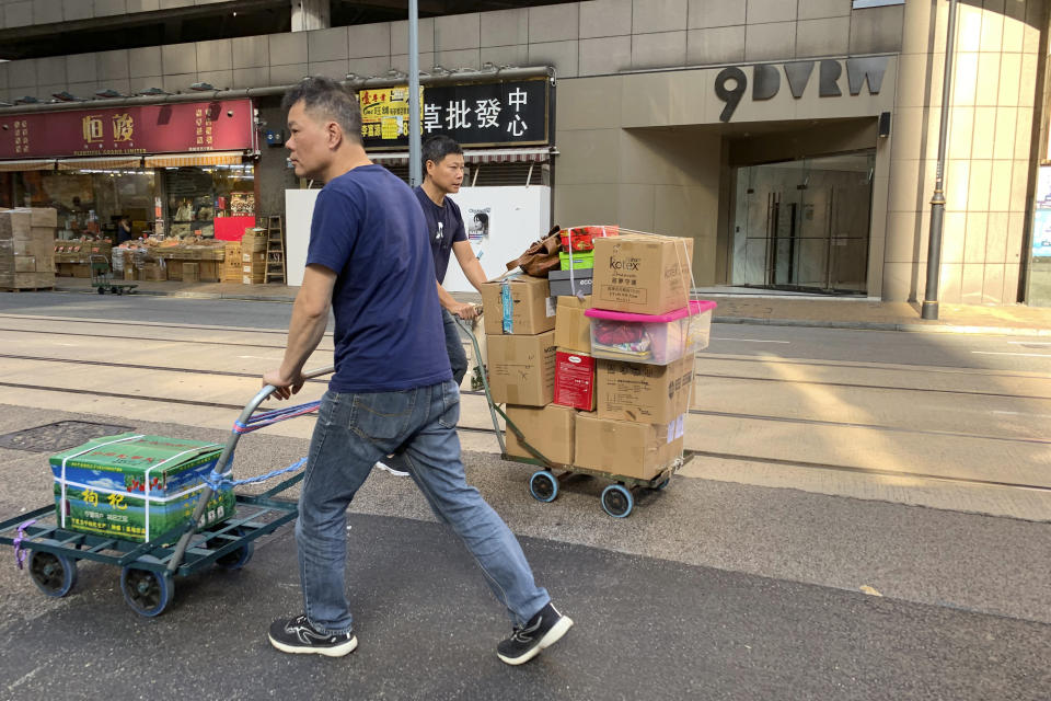 Workers walk past a building listed as the address of China Innovation Investment Limited in Hong Kong, Saturday, Nov. 23, 2019. Australia’s Treasurer on Saturday labeled detailed accusations of China infiltrating and disrupting democratic systems in Australia, Hong Kong and Taiwan as “very disturbing”. A Chinese defector revealed he was part of the Hong Kong-based investment firm, which was a front for the Chinese government to conduct political and economic espionage in Hong Kong, including infiltrating universities and directing bashings and cyber attacks against dissidents. (AP Photo/Ng Han Guan)