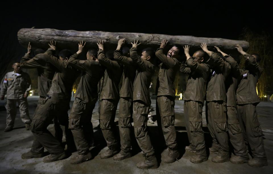 Students carry tree trunk over their heads during high intensity training at Tianjiao Special Guard/Security Consultant camp on the outskirts of Beijing