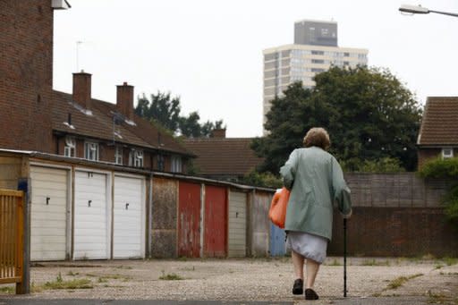 A woman walks past garages near the High Street in Stratford, east London on August 15, 2012. London may have basked in the euphoria of a successful Olympics in 2012 but now that the party is over, local people are wondering if its legacy can improve the deprived area which hosted the Games