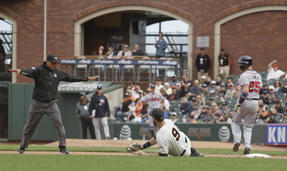 Atlanta Braves' Tyler Flowers makes it safely to first base as San Francisco Giants first baseman Brandon Belt (9) looks for the ruling from umpire Jeremie Rehak during the ninth inning of a baseball game Wednesday, Sept. 12, 2018, in San Francisco. The Braves' Charlie Culberson scored a run on the play. Atlanta won the game 2-1. (AP Photo/Eric Risberg)