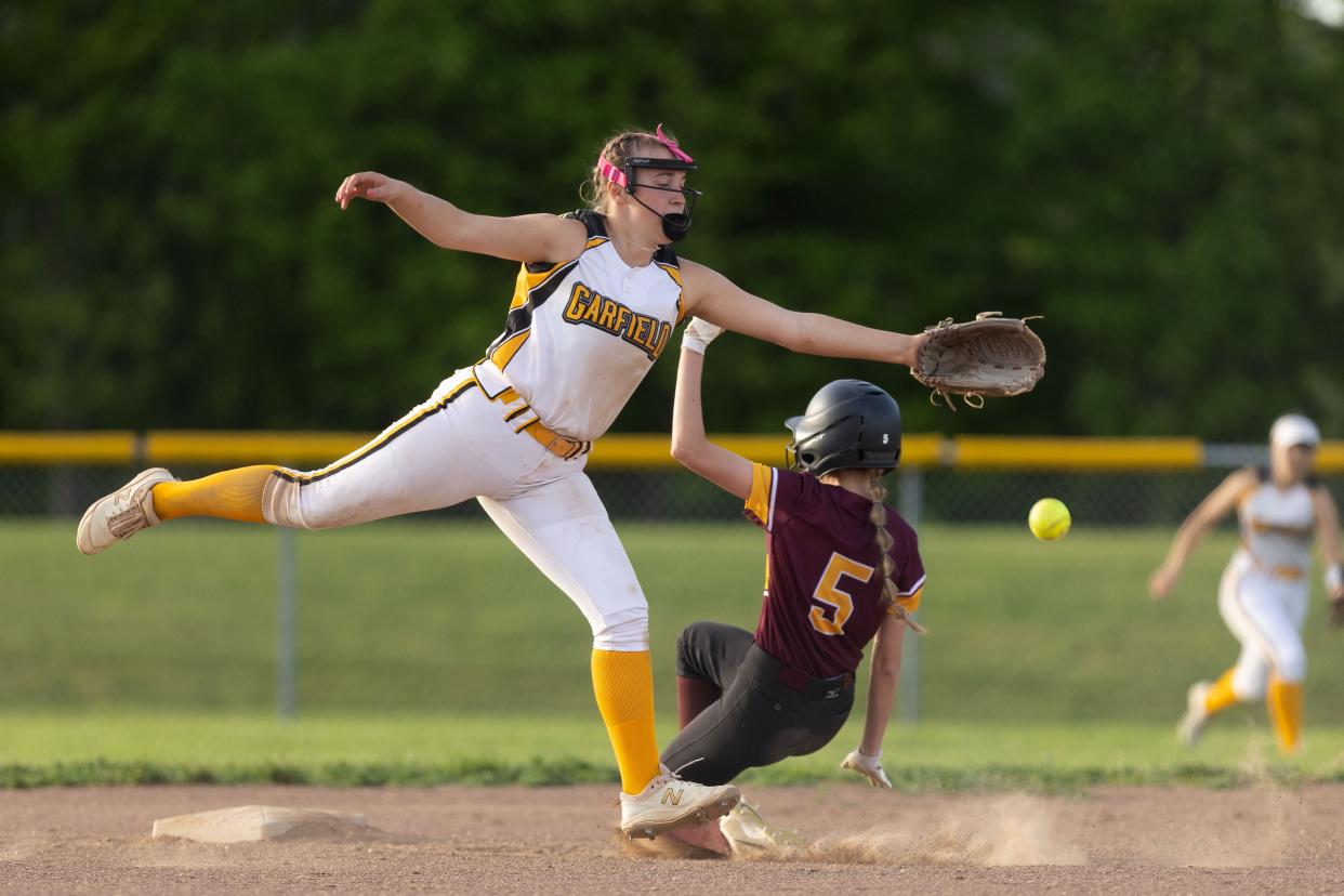 Southeast’s Mya Sutcliffe slides into second as Garfield shortstop Juliana Genovese leaps to try and catch the ball during Wednesday night’s game in Garrettsville.