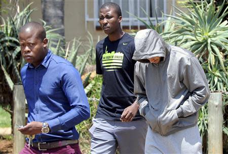 South African "Blade Runner" Oscar Pistorius (R) is escorted by police at a Pretoria police station February 14, 2013. REUTERS/Stringer