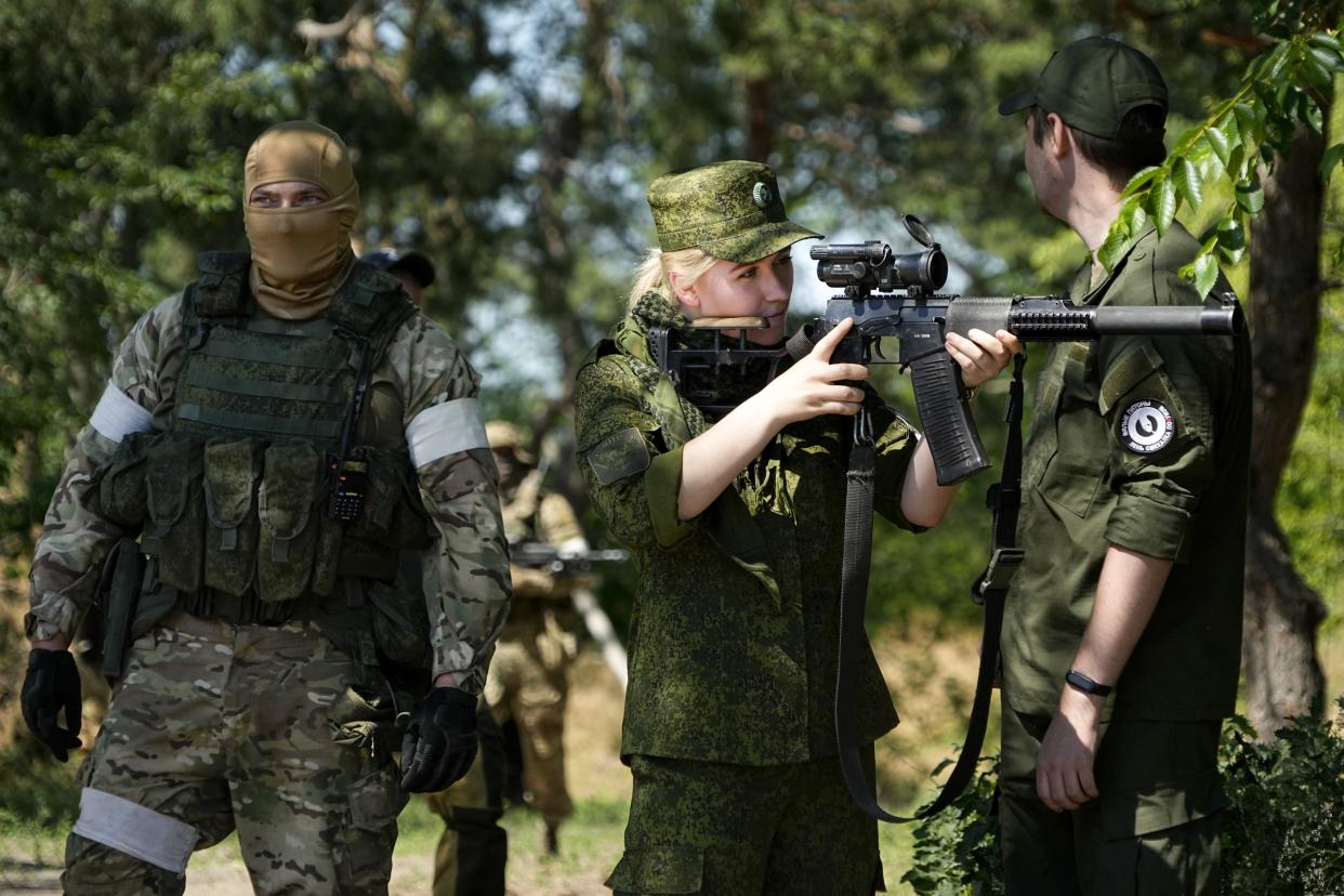 FILE - A Russian Army soldier looks through a sniper rifle scope as she and other soldiers guard a group of foreign journalists visiting a captured Ukrainian checkpoint and well-fortified trenches near Schastia town, on the territory which is under the Government of the Luhansk People's Republic control, eastern Ukraine, Saturday, June 11, 2022. Despite getting bogged down in Ukraine, the Kremlin has resisted announcing a full-blown mobilization, a move that could prove to be very unpopular for President Vladimir Putin. That has led instead to a covert recruitment effort that includes trying to get prisoners to make up for the manpower shortage. This photo was taken during a trip organized by the Russian Ministry of Defense. (AP Photo, File)