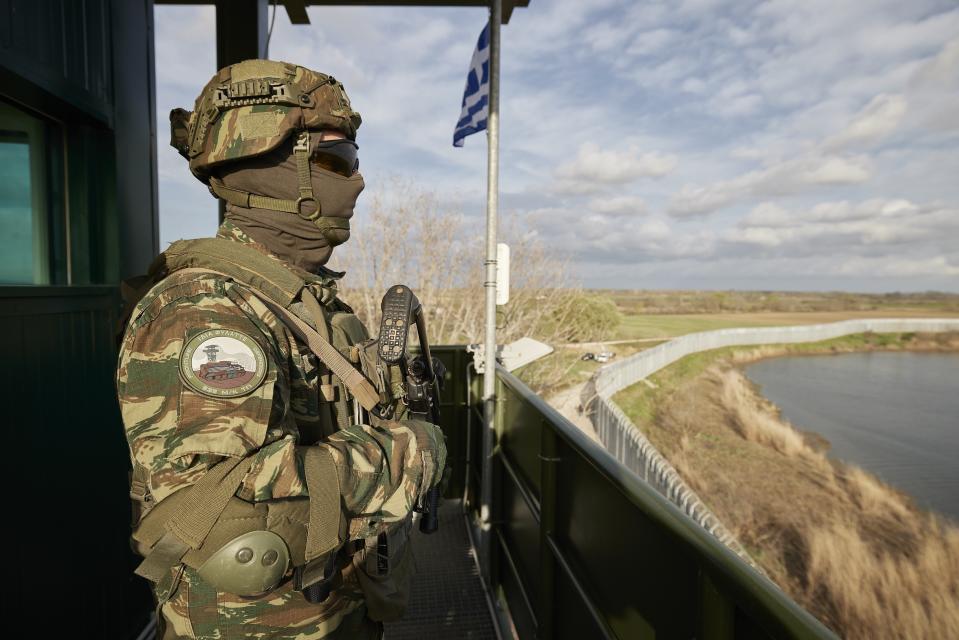 In this photo provided by the Greek Prime Minister's Office, a Greek soldier guards over a border wall near the town of Feres, along the Evros River which forms the frontier between Greece and Turkey, on Friday, March 31, 2023. Greece's Prime Minister Kyriakos Mitsotakis promised Friday to extend a wall across all of the country's land border with Turkey as he campaigned for the country's general election. (Dimitris Papamitsos/Greek Prime Minister's Office via AP)