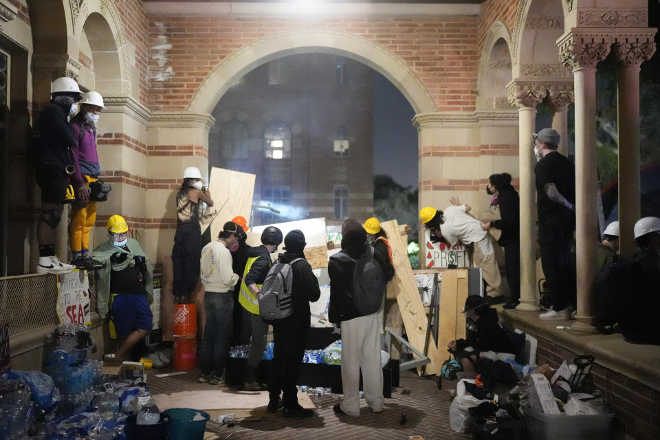 Pro-Palestinian demonstrators watch police activity behind a makeshift barricade on the UCLA campus Wednesday, May 1, 2024, in Los Angeles. (AP Photo/Jae C. Hong)