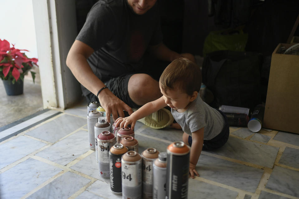 Street artist Wolfgang Salazar takes inventory of his aerosol paints accompanied by his son Noah, in their home in the Petare neighborhood of Caracas, Venezuela, Monday, Dec. 28, 2020. Salazar has gained increasing fame for his spray-painted murals of Venezuelans — heroes and everyday folk alike. “The main goal is that people see a reflection of themselves,” said Salazar, who added that he hopes people will see the murals and say: “I exist. What happens to me exists. I’m real. I feel identified." (AP Photo/Matias Delacroix)