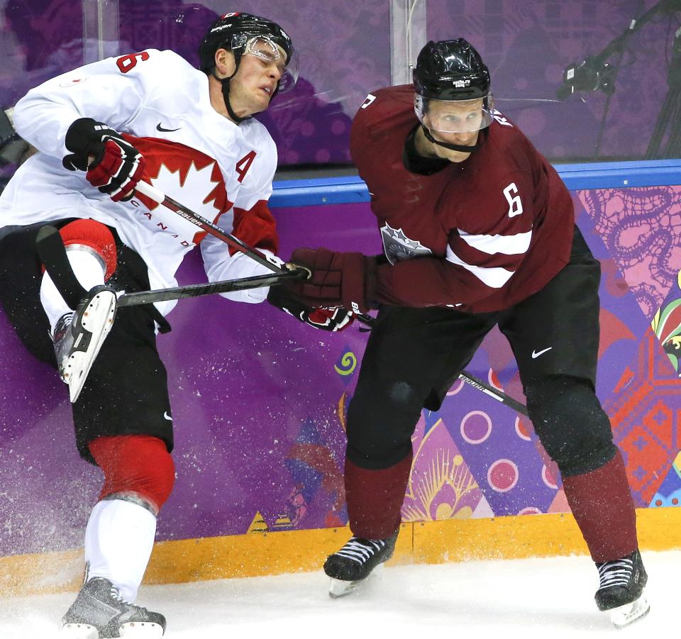 Canada forward Jonathan Toews, at left, is checked by Latvia defenseman Arvids Rekis, at right during the second period of a men's quarterfinal ice hockey game, Feb. 19, 2014, at the 2014 Winter Olympics in Sochi, Russia. Rekis, who played for the Otters from 1996-2000, represented Latvia at the 2006, 2010 and 2014 Winter Olympics.