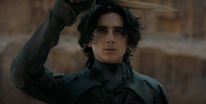 Timothée as Paul in "Dune," he holds a sword over his forehead perpendicular to his body