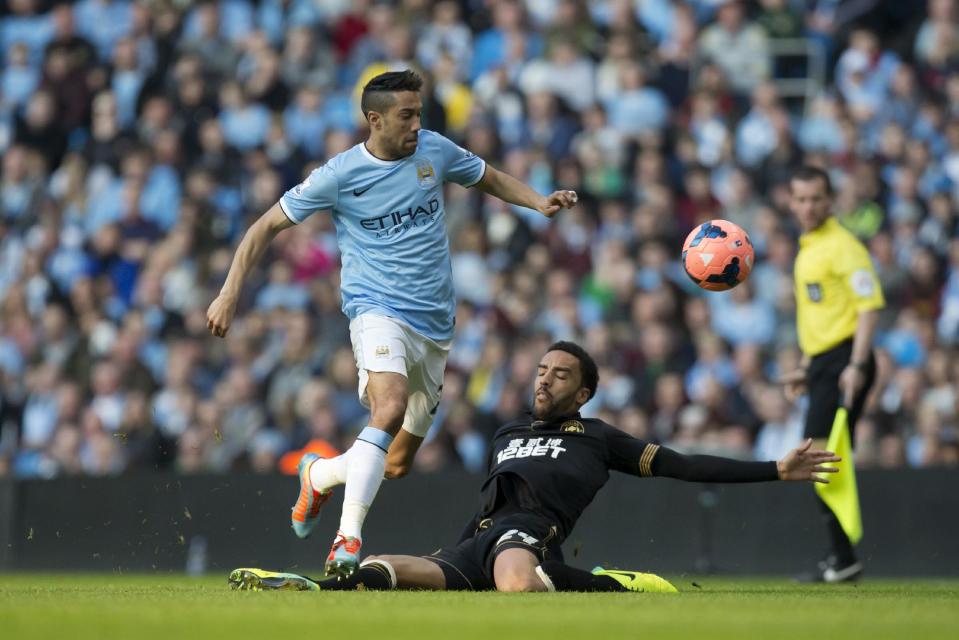 Manchester City's Gael Clichy, centre, avoids a tackle by Wigan's James Perch during their English FA Cup quarterfinal soccer match at the Etihad Stadium, Manchester, England, Sunday, March 9, 2014. (AP Photo/Jon Super)