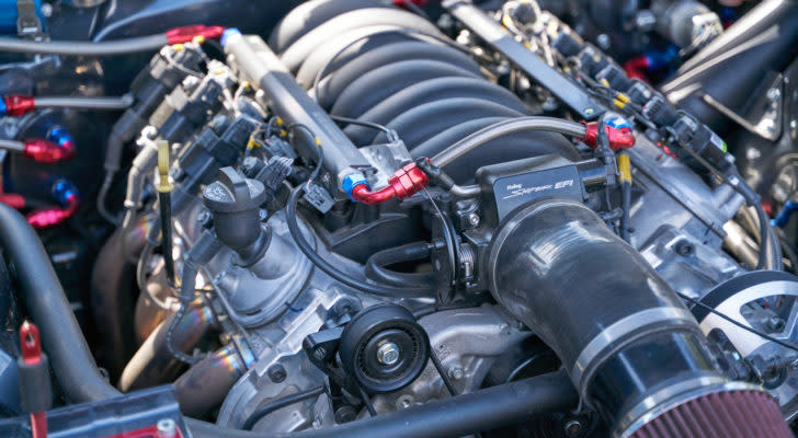 A close-up photograph of a car engine representing SINT Stock.