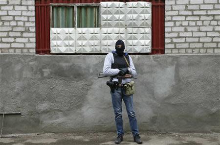 An armed man stands in front of the police headquarters building in Slaviansk, April 12, 2014. REUTERS/Gleb Garanich