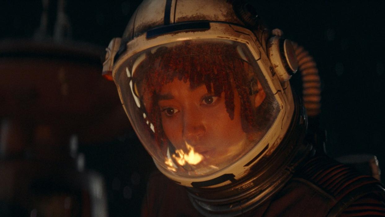  Amandla Sternberg's Mae looking at a fire while repairing the outside of a ship in The Acolyte . 