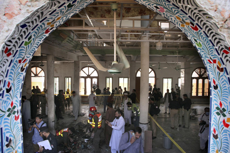 Pakistani rescue workers and police officers examine the site of a bomb explosion in an Islamic seminary, in Peshawar, Pakistan, Tuesday, Oct. 27, 2020. A powerful bomb blast ripped through the Islamic seminary on the outskirts of the northwest Pakistani city of Peshawar on Tuesday morning, killing some students and wounding dozens others, police and a hospital spokesman said. (AP Photo/Muhammad Sajjad)