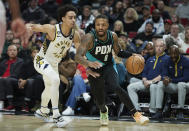 Portland Trail Blazers guard Damian Lillard, right, dribbles around Indiana Pacers guard Andrew Nembhard during the second half of an NBA basketball game in Portland, Ore., Sunday, Dec. 4, 2022. (AP Photo/Craig Mitchelldyer)