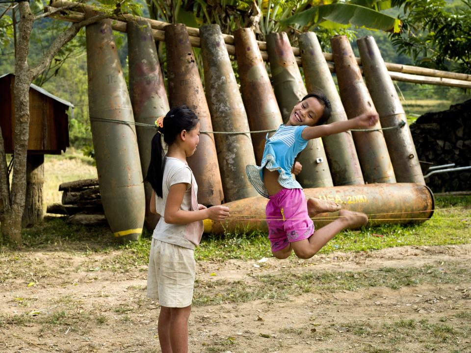 Children play in home in front of several large unexploded bombs