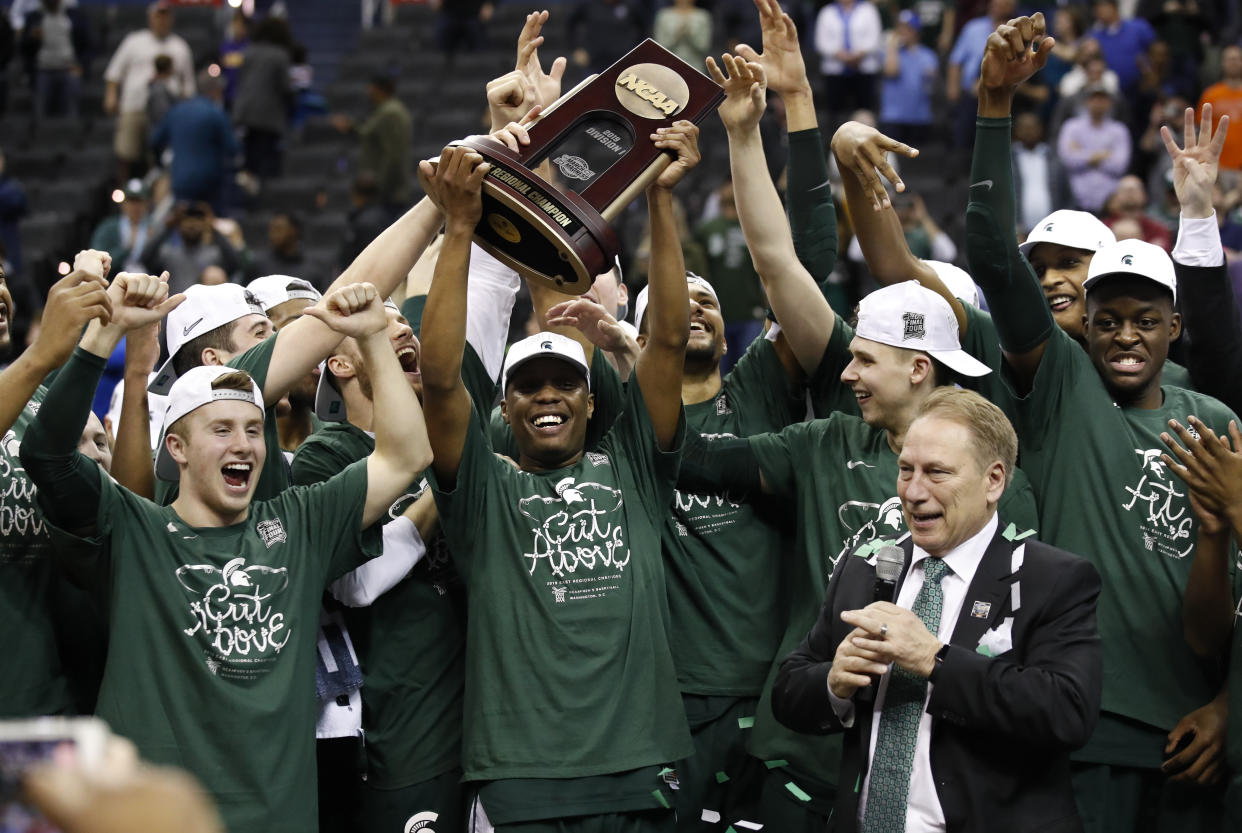 Michigan State guard Cassius Winston holds up the NCAA men's East Regional trophy as he celebrates with his team after defeating Duke in a college basketball game in Washington, Sunday, March 31, 2019. Michigan State won 68-67. (AP Photo/Alex Brandon)
