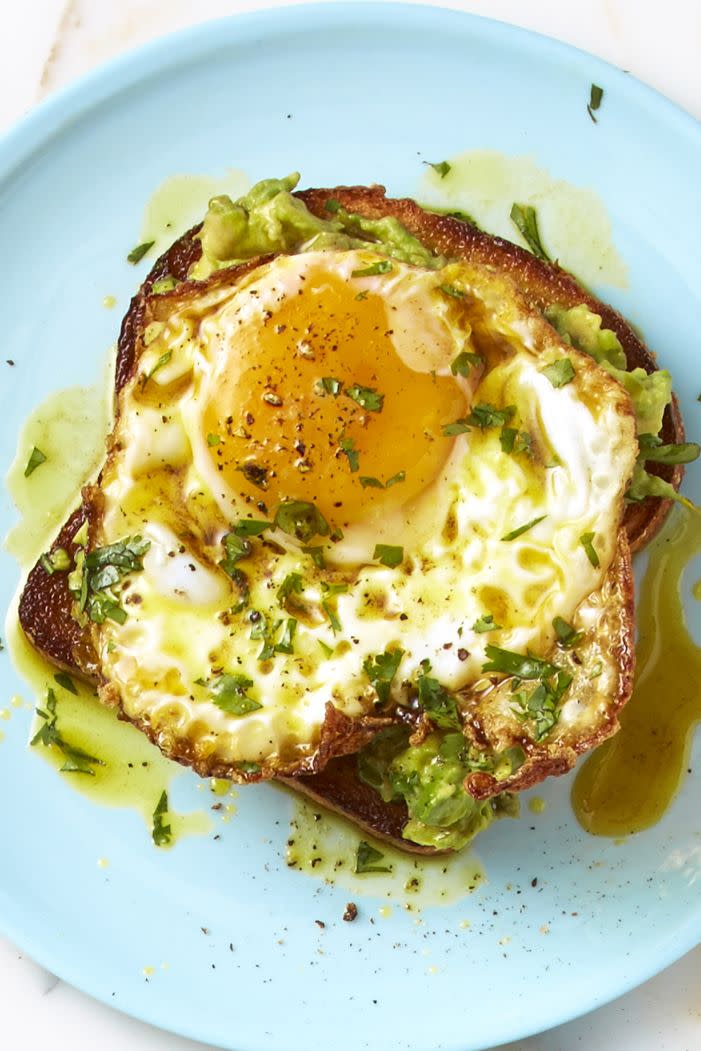 curry avocado egg toast sprinkled with herbs on a blue plate