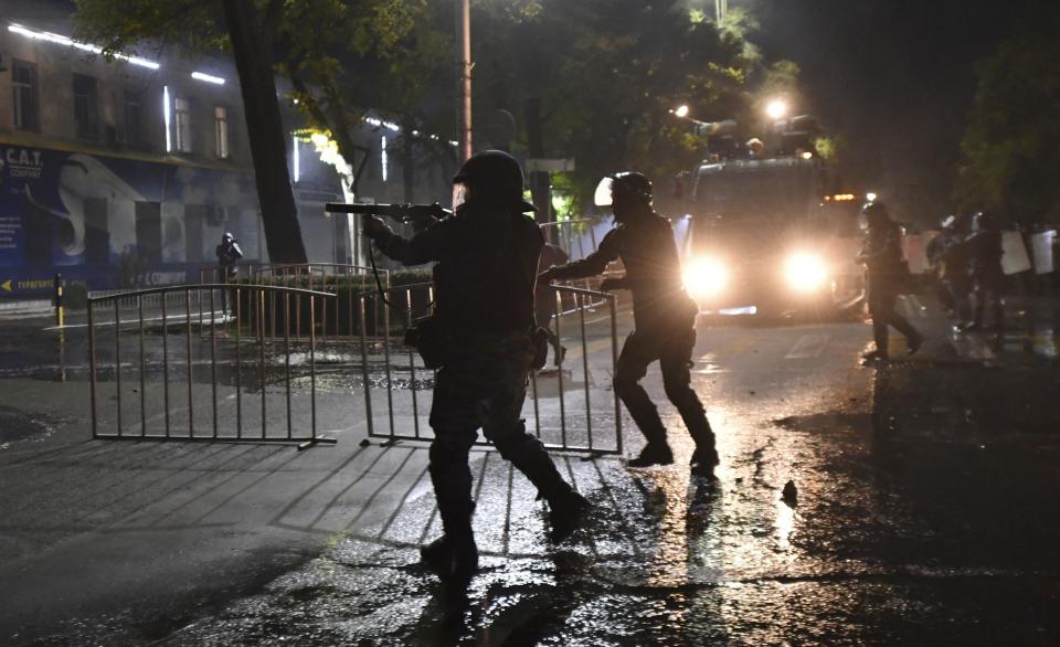 Riot police disperse protesters during a rally against the results of a parliamentary vote in Bishkek, Kyrgyzstan, Monday, Oct. 5, 2020. Large crowds of people have gathered in the center of Kyrgyzstan's capital to protest against the results of a parliamentary election, early results of which gave the majority of seats to two parties with ties to the ruling elites amid allegations of vote buying. (AP Photo/Vladimir Voronin)