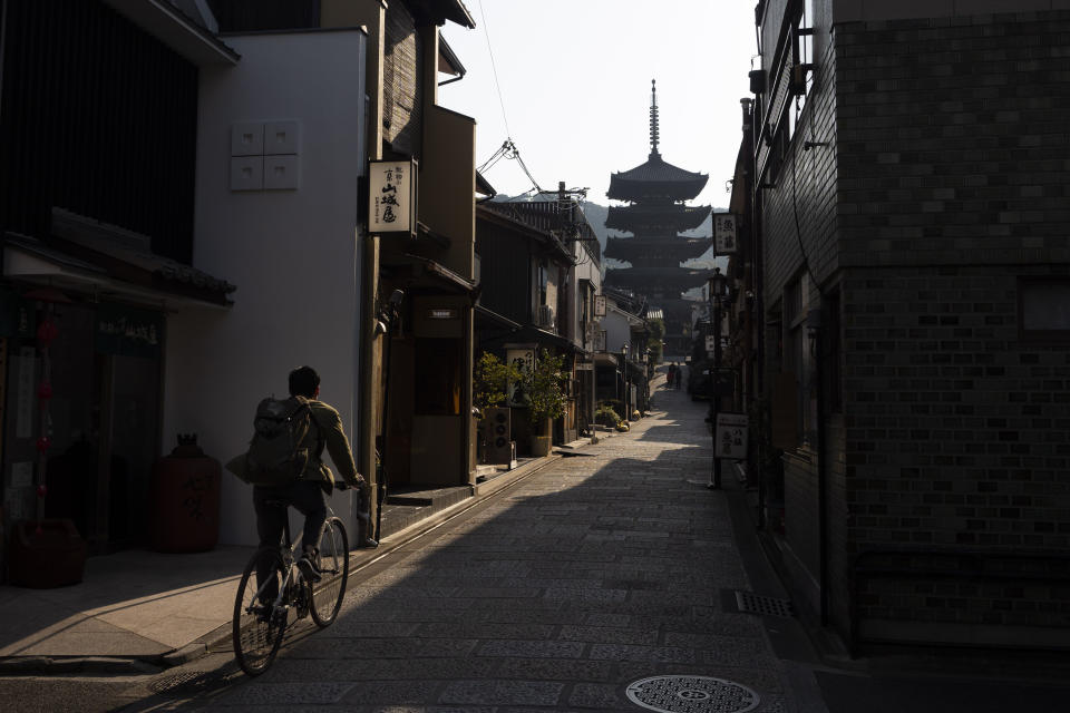 A man rides his bike toward Yasaka Pagoda in the Higashiyama district of Kyoto, Japan, March 19, 2020. Kyoto's city government has an emergency fund for small to medium-size businesses who suffered sharp sales decline since the coronavirus outbreak. (AP Photo/Jae C. Hong)