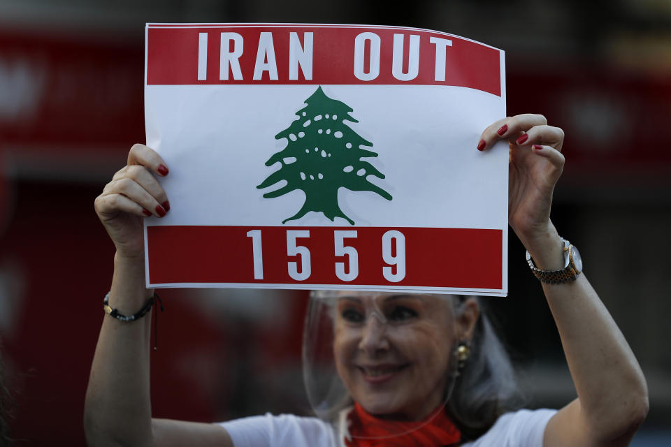 A Lebanese protester holds a placard during a protest against the Hezbollah group and the visit of the Iranian Foreign Minister Hossein Amirabdollahian who will meet with Lebanese officials on Thursday, in Beirut, Lebanon, Wednesday, Oct. 6, 2021. (AP Photo/Hussein Malla)