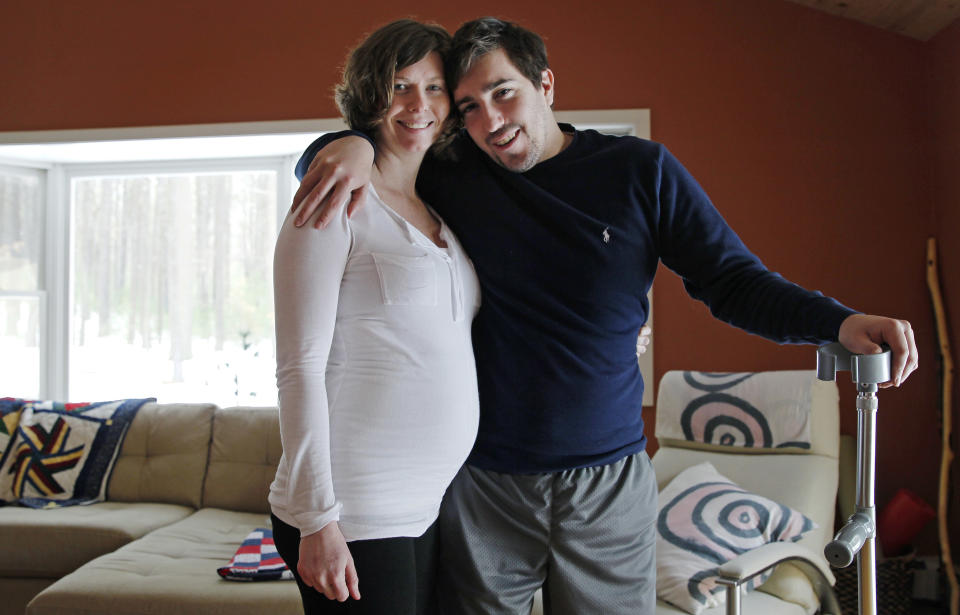 ADVANCE FOR WEEKEND USE APRIL 4-5 -- In this March 14, 2014 photo, Jeff Bauman, who lost both his legs above the knee in the Boston Marathon bombing, poses with his fiancee Erin Hurley at their Carlisle, Mass., home. The couple are expecting their first child in July. (AP Photo/Charles Krupa)