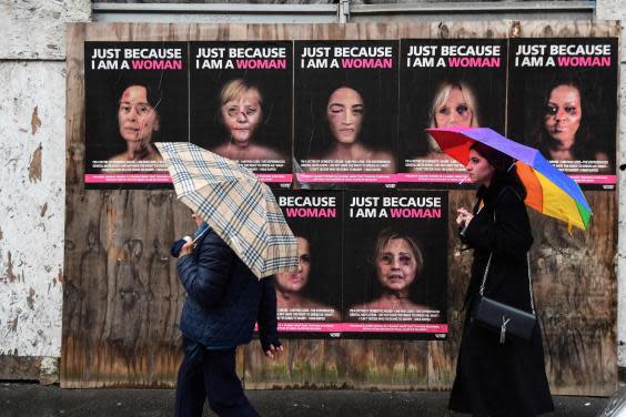 People walk past ‘Just because I am a Woman’, a new series of works by Italian artist aleXsandro Palombo, depicting women in politics as victims of gender violence (AFP via Getty Images)