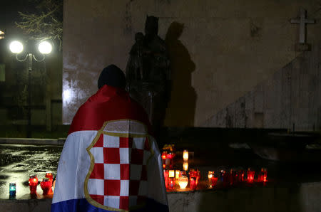 A Bosnian Croat, wrapped in a flag of unrecognised wartime Croat statelet, prays for the convicted general Slobodan Praljak who killed himself seconds after the verdict in the U.N. war crimes tribunal in The Hague, in Mostar, Bosnia and Herzegovina November 29, 2017. REUTERS/Dado Ruvic