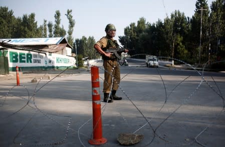 An Indian security personnel stands guard on a deserted road during restrictions after scrapping of the special constitutional status for Kashmir by the Indian government, in Srinagar