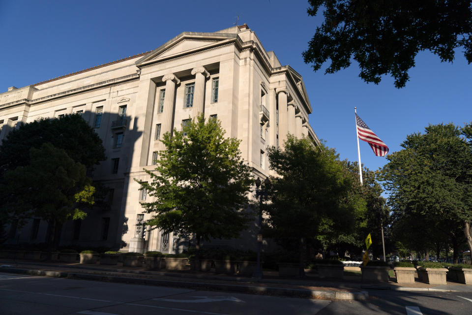 FILE - In this Oct. 8, 2020, file photo an American flag flies outside of the Justice Department building in Washington. The elite Russian hackers who gained access to computer systems of federal agencies last year didn’t bother trying to break one-by-one into the networks of each department. Instead, they got inside by sneaking malicious code into a software update pushed out to thousands of government agencies and private companies. (AP Photo/Jacquelyn Martin, FIle)