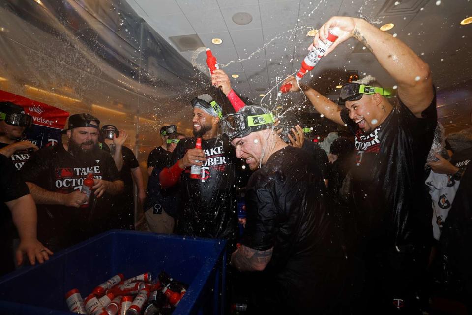 <p>David Berding/Getty</p> Minnesota Twins players shower each other in champagne after first postseason series victory in 21 years