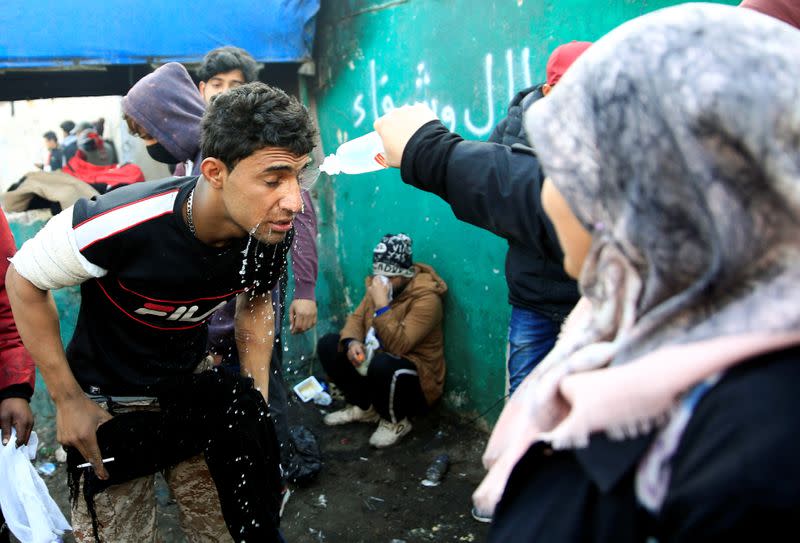 A woman splashes water on an Iraqi demonstrator's face during ongoing anti-government protests in Baghdad