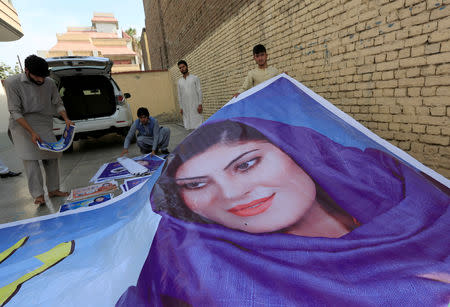 Supporters of female Afghan parliamentary election candidate, Dewa Niazai, prepare to install a poster of her during a election campaign in Jalalabad, Afghanistan October 4, 2018. REUTERS/Parwiz