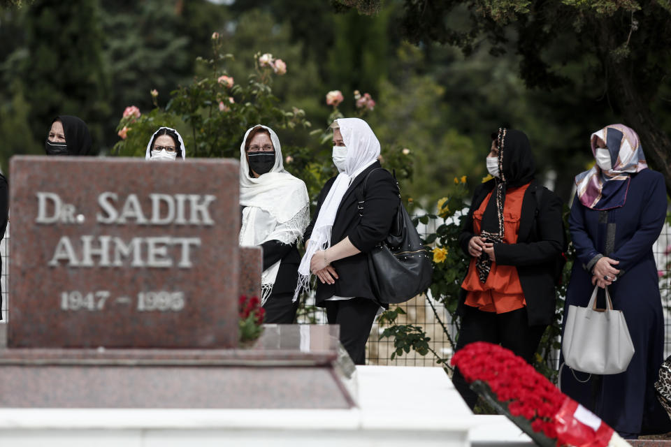 Women stand around the grave of Ahmet Sadik, who was an MP at the Greek parliament, at a muslim cemetery at Komotini town, in northeastern Greece, Sunday, May 30, 2021. Greece's prime minister said Friday his country is seeking improved ties with neighbor and longtime foe Turkey, but that the onus is on Turkey to refrain from what he called "provocations, illegal actions and aggressive rhetoric." (AP Photo/Giannis Papanikos)