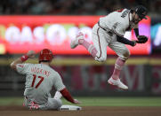 Atlanta Braves' Dansby Swanson, right, hops over Philadelphia Phillies' Rhys Hoskins (17) after completing a double play during the seventh inning of a baseball game Sunday, May 9, 2021, in Atlanta. Phillies' Odubel Herrera was out at first base. (AP Photo/Ben Margot)