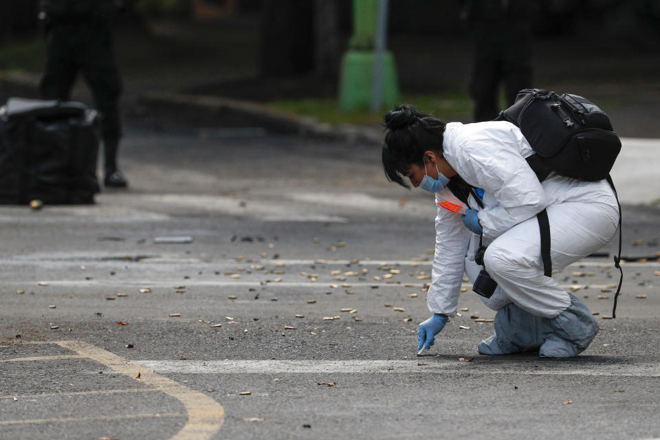 A forensic investigator collects cartridges at the scene where the Mexican capital's police chief was attacked by gunmen in Mexico City, Friday, June 26, 2020. Heavily armed gunmen attacked and wounded Omar García Harfuch in an operation that left several dead. (AP Photo/Rebecca Blackwell)