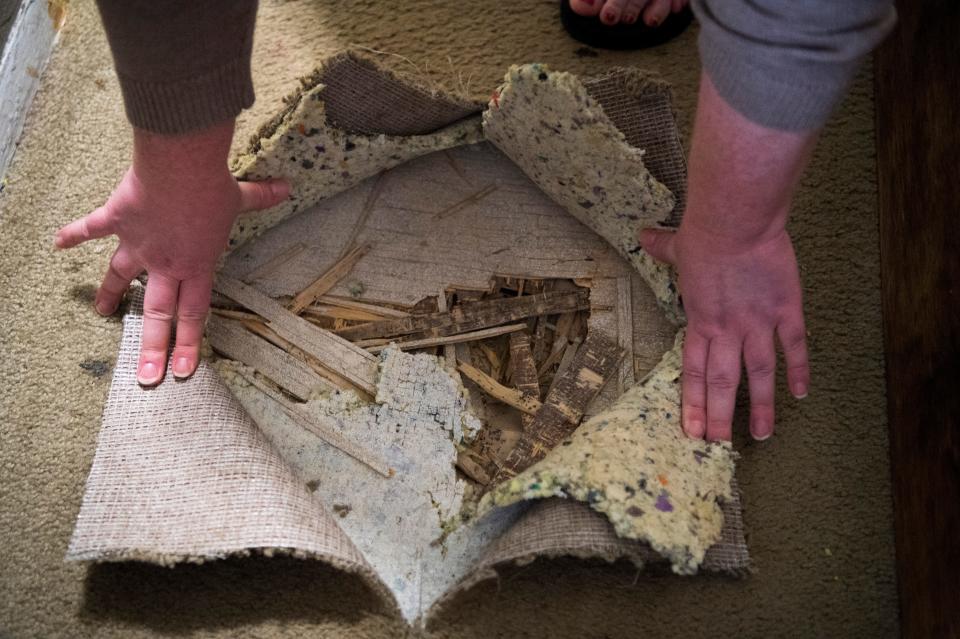 Martin Park East resident Melissa Froust pulls back carpet to show a hole in her floor Friday, May 6, 2022. 