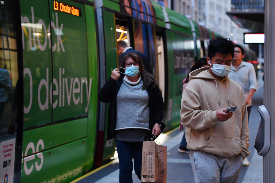 Commuters hop of a tram wearing face masks in Sydney. Source: AAP