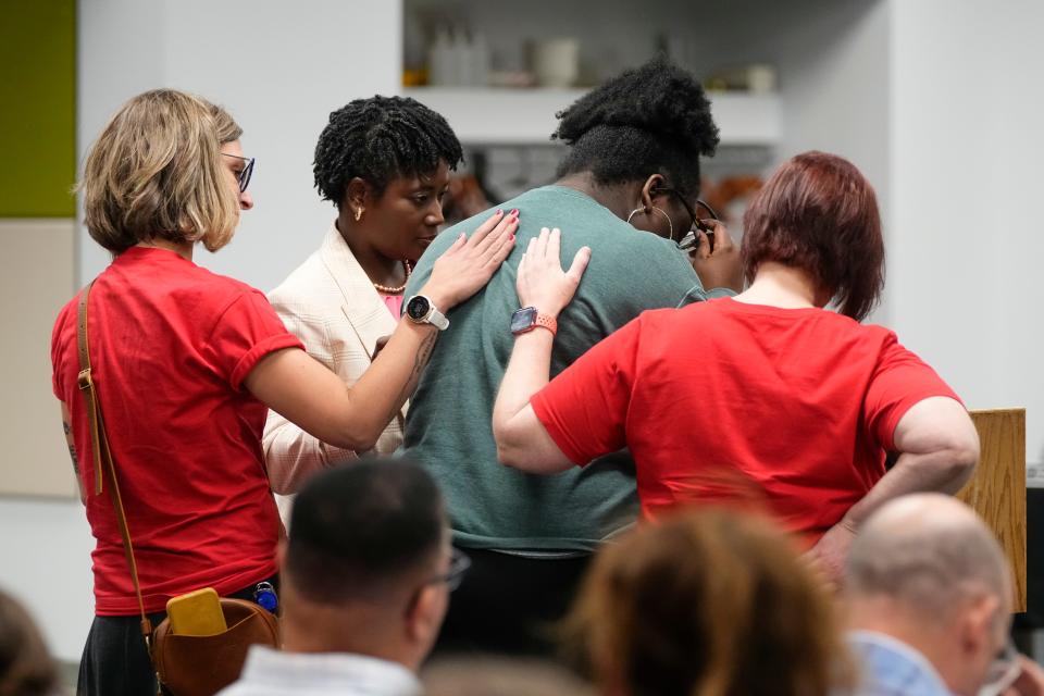 Audience members help console Independence High School senior Josephine Amponsah as she speaks out against the potential closing of schools during public comment Tuesdy at a Columbus City School Board meeting.