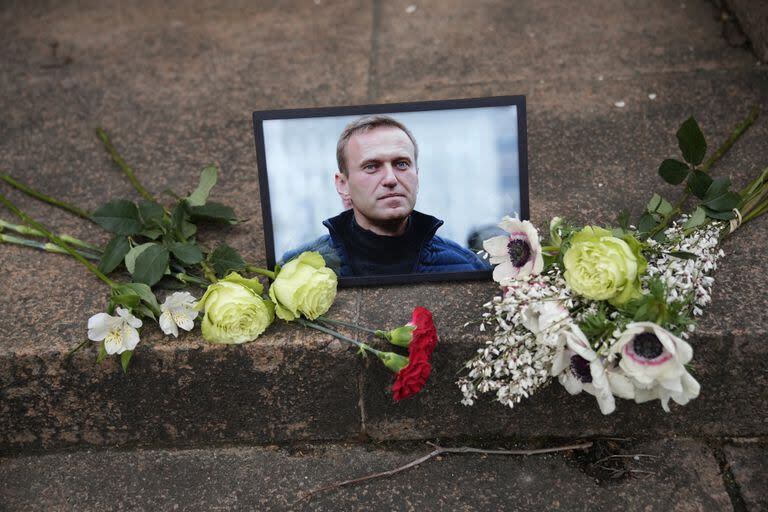 Un retrato del líder de la oposición Alexei Navalny y flores mientras la gente se manifiesta cerca de la embajada rusa en Francia, el viernes 16 de febrero de 2024 en París.