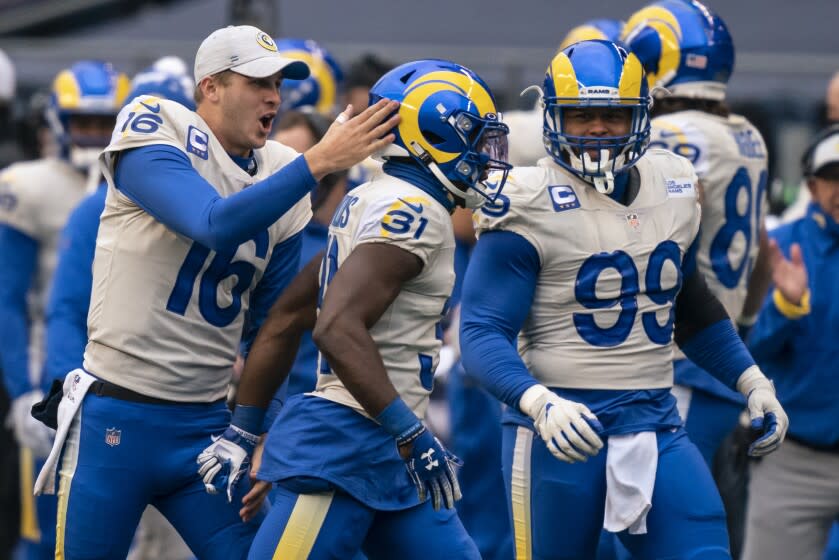 Los Angeles Rams quarterback Jared Goff and defensive lineman Aaron Donald (99) celebrate defensive back Darious Williams' (31) interception returned for a touchdown during the first half of an NFL wild-card playoff football game against the Seattle Seahawks, Saturday, Jan. 9, 2021, in Seattle. The Rams won 30-20. (AP Photo/Stephen Brashear)