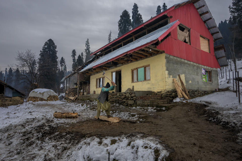 A Kashmiri man chops firewood outside his home in Drang village northwest of Srinagar, Indian controlled Kashmir Friday, Dec. 22, 2023. In the hilly areas of Kashmir, most villagers depend on firewood for cooking and heating during the winter season. (AP Photo/Dar Yasin)