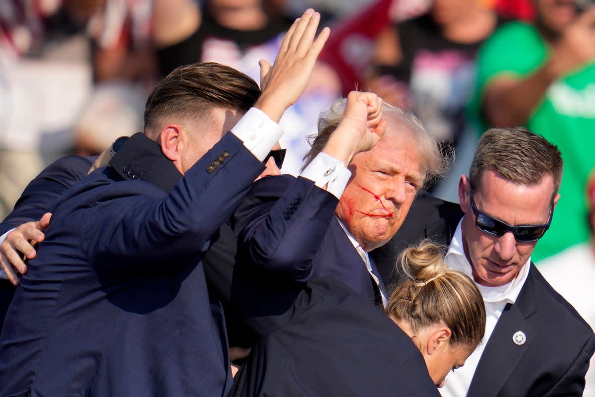 Donald Trump is helped off the stage by US Secret Service agents