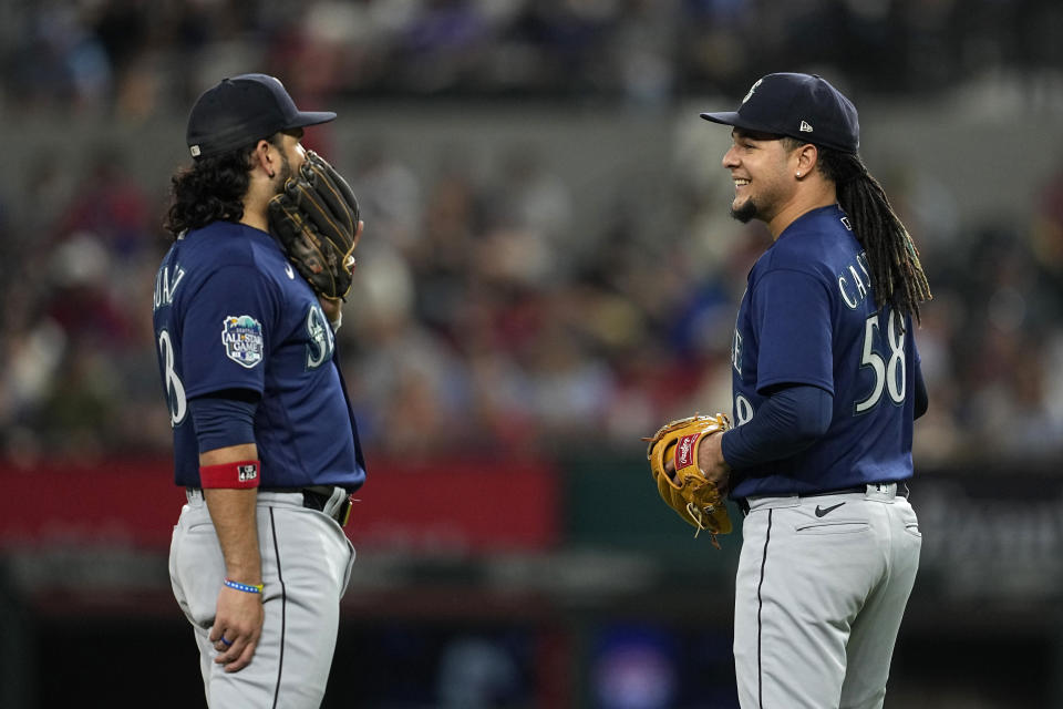 Seattle Mariners third baseman Eugenio Suarez, left, talks with starting pitcher Luis Castillo after Castillo gave up his first hit of the night, a single to Texas Rangers' Robbie Grossman, during the fifth inning of a baseball game Friday, June 2, 2023, in Arlington, Texas. (AP Photo/Tony Gutierrez)