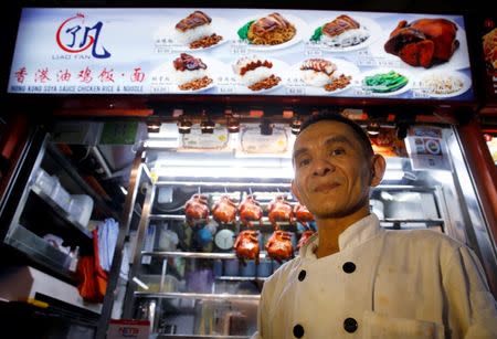 Hawker Chan Hong Meng, who earned a Michelin star for his soya sauce chicken rice and noodle, poses for the media outside his stall at a food market in Singapore, July 22, 2016. REUTERS/Edgar Su