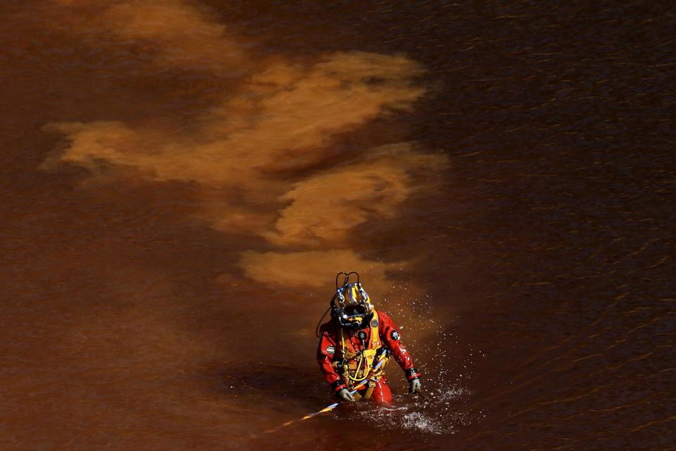 A diver walks out from a toxic man-made lake after a dive search for a third victim (AP)