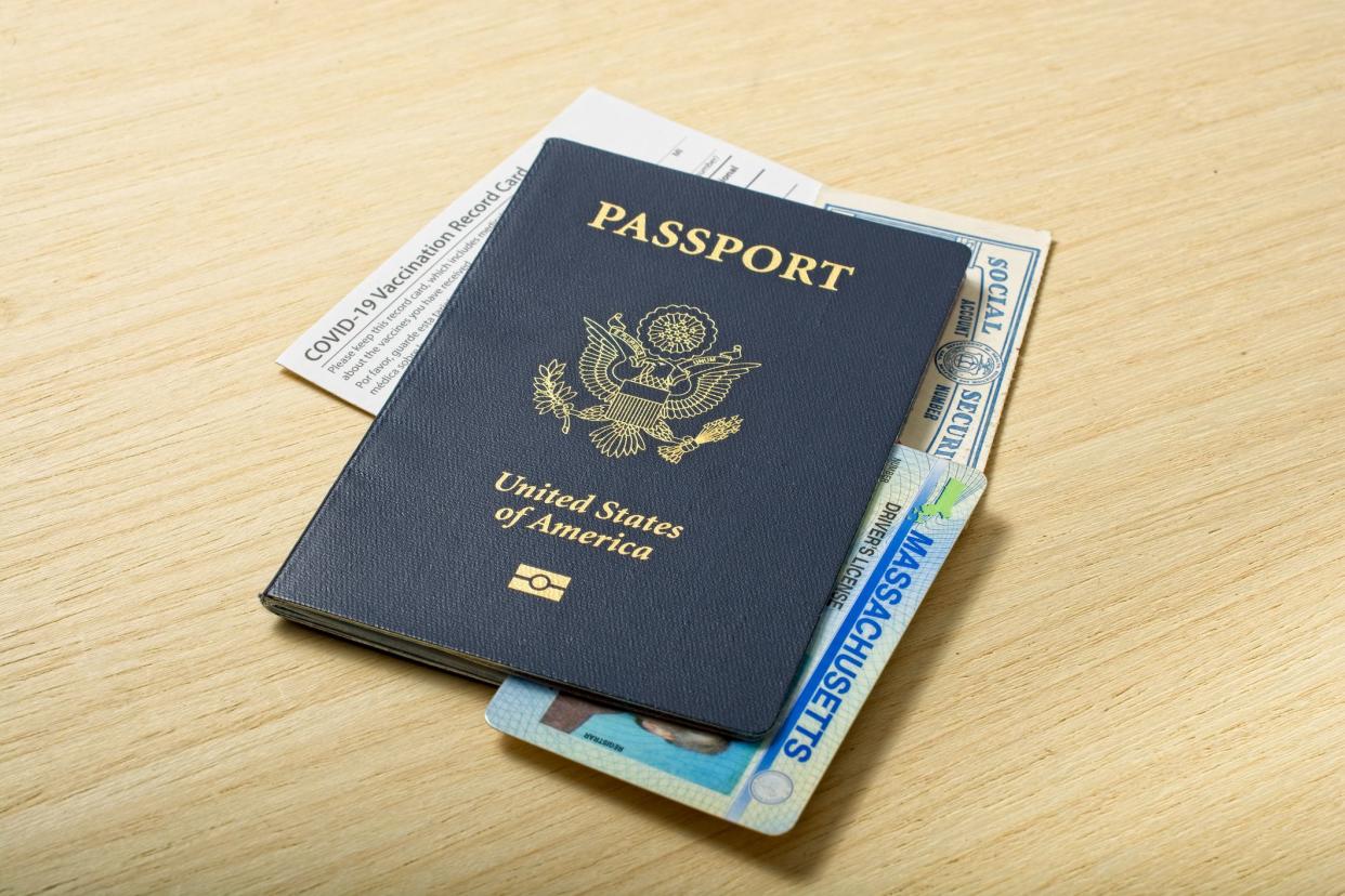 Contemporary Personal Identification Information set of passport Social Security Real ID and COVID-19 Vaccination card all lying on  wooden tabletop.