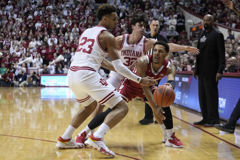 Wisconsin's Jordan Davis (2) makes a pass as Indiana's Trayce Jackson-Davis (23) and Trey Galloway (32) defend during the first half of an NCAA college basketball game, Saturday, Jan. 14, 2023, in Bloomington, Ind. (AP Photo/Darron Cummings)